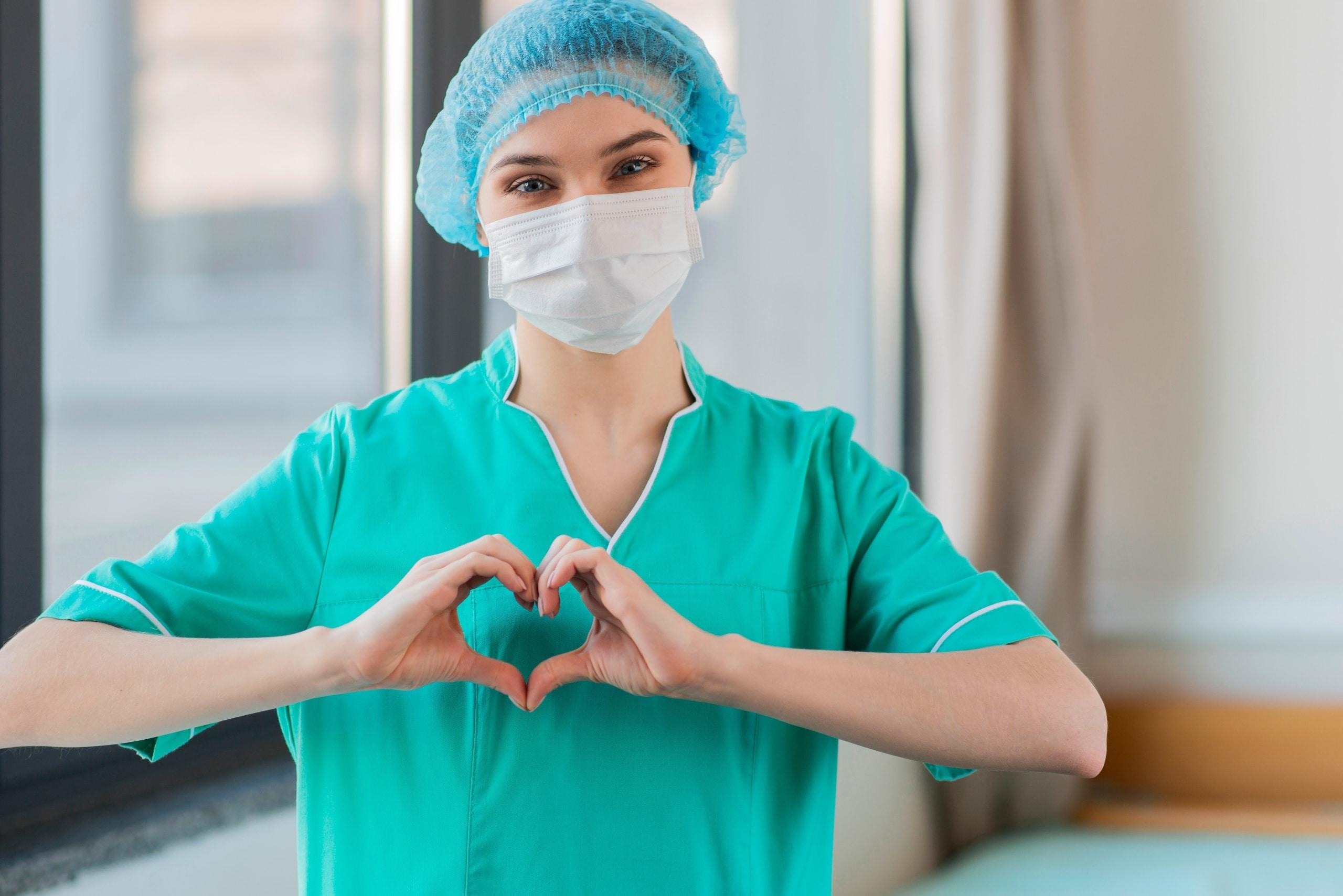 Masked nurse forming a heart with her hands